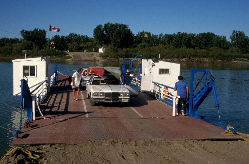 Canoe and car riding the Estuary Ferry across the South Saskatchewan River.