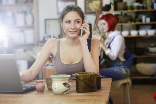 Photo of a potter doing administrative work in her studio.